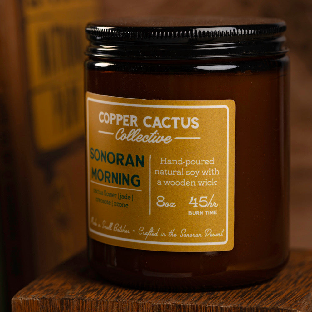 Candle jar with 'Copper Cactus Collective' label on a wooden surface