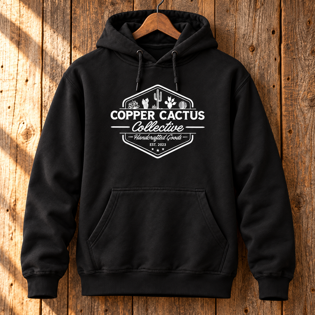 Black Copper Cactus logo hoodie on a wooden hanger against rustic barn wood