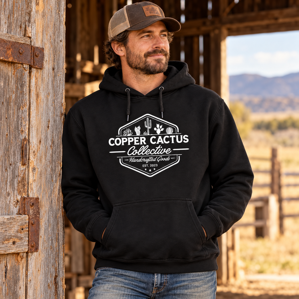 Man wearing black Copper Cactus logo hoodie at a barn doorway