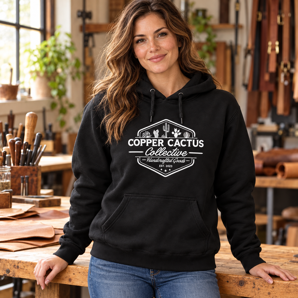 Woman wearing black Copper Cactus logo hoodie in a leatherworking studio